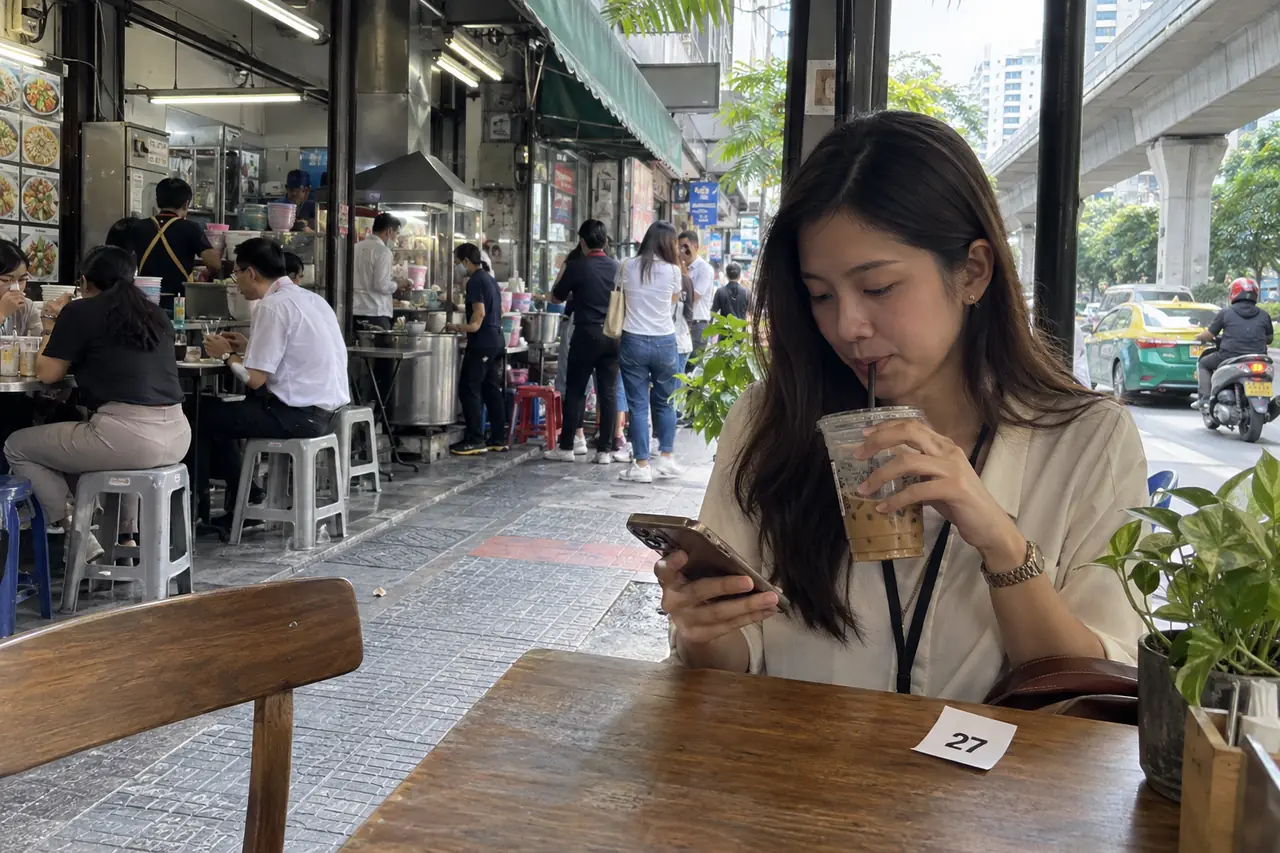 ลูกค้านั่งรอในร้านกาแฟข้างๆ ถือมือถือและใบคิวหมายเลข 27